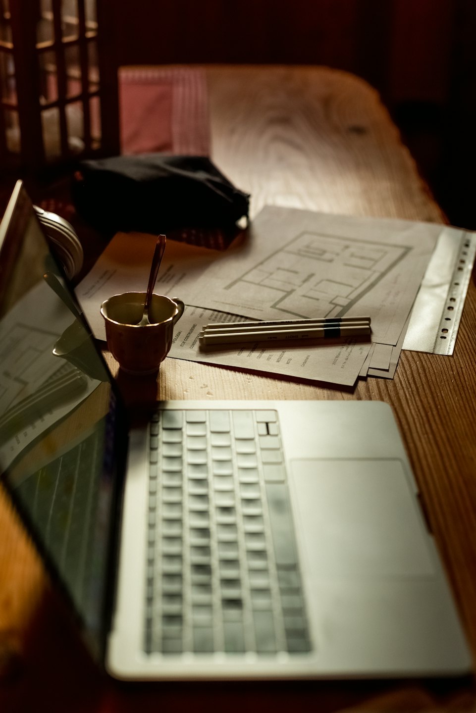 Laptop und Baupläne auf einem Holztisch.